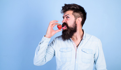 That is how tastes summer. Man handsome hipster with long beard licking strawberry tongue. Hipster enjoy juicy ripe red strawberry. Man enjoy berry aroma. Berries season concept. Oral pleasure
