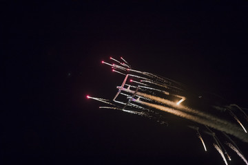 Planes performing night airshow in the night with fireworks at Torre del Mar International Airshow in Malaga, Spain. - obrazy, fototapety, plakaty