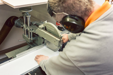 Tinner cutting metal sheets in his workshop with saw, close-up 