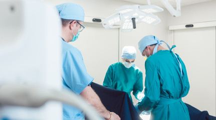 View on team of surgeons operating over monitor and equipment in hospital 