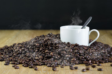 White Cup of hot black coffee in pile of coffee seeds new roasted hot and which has smoke