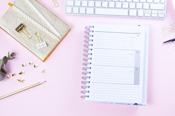 Flat lay home office workspace - white modern keyboard with notebook on pink desk background