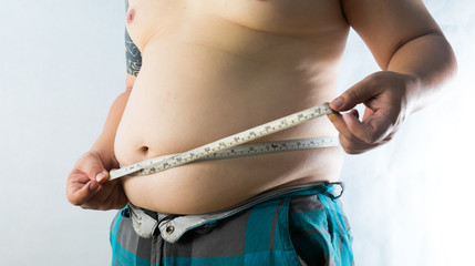 fat man check out his body fat with measuring tape for fat or obesity background