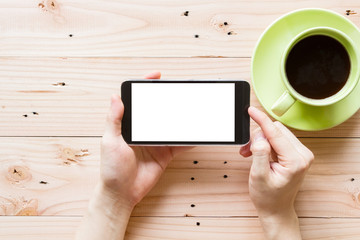 Fototapeta na wymiar hand using mobile smart phone with blank white screen on wooden background