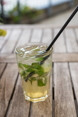 Natural lemonade with lime and mint in glass on wooden table in a outdoor restaurant
