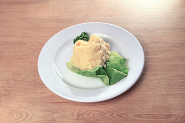 mashed potatoes with salad on white plate on wooden background