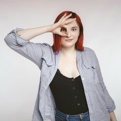 Red haired plus size ordinary woman standing on a neutral grey background. Emotional portrait. She...