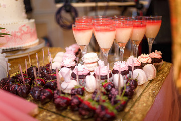 strawberries in the dark chocolate, cupcakes, macaroons and milk jelly in the goblets