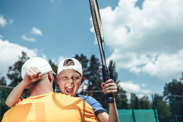 I am proud of you. Satisfied boy embracing parent while gesticulating hands with racket on court....