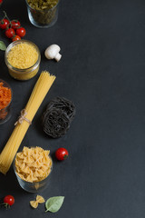 Different types of Italian pasta with vegetables on the dark chalkboard