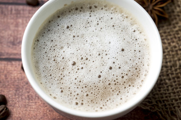 White coffee Cup and saucer with milk foam and cane sugar cinnamon Anise Coffee beans