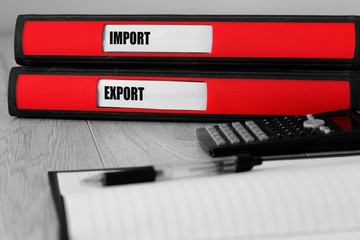 Red folders with import and export written on the label on a desk with selective colour