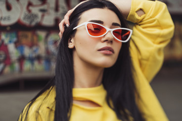 Sexy slim fit brunette woman in sport casual outfit in a skate park. Summer sunny day