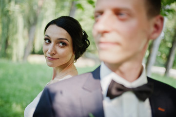 Close-up portrait of an attractive bride looking at her husband in the park.