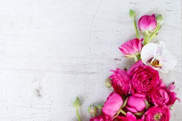 Flowers composition made of fresh ranunculus and orchid flowers on white aged wooden background. Flat lay, top view, copy space