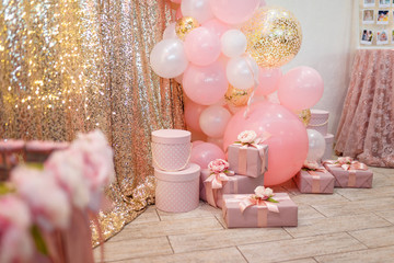 girl birthday decoration with pink baskets, flowers, presents and balloons on the golden background