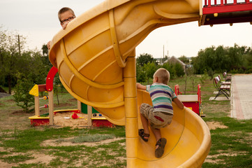 Happy village children came to city to play in playground. Funny child is riding toy car with...