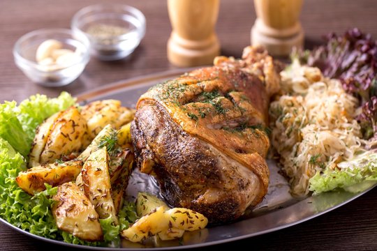 Juicy roasted pork knuckle with baked potato and sauerkraut