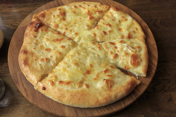 Fresh cheese pizza on a wooden plate on the table, Italian traditional appetizer, high angle view.