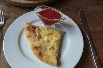 Slice of fresh cheese pizza in a plate, jug with spicy ketchup. Italian traditional appetizer.