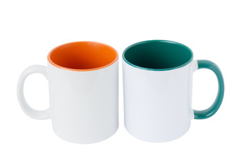 Two white mugs, with a green and orange handle on a light background. Isolated.