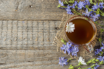 Chicory drink in Cup and flowers on rustic wooden background. Medicinal plant Cichorii.