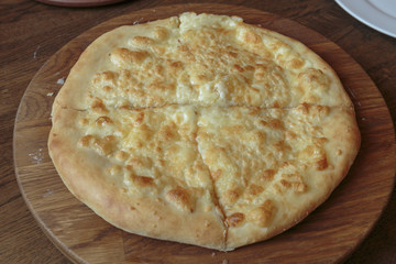 Fresh cheese pizza on a wooden plate on the table, Italian traditional appetizer, high angle view.