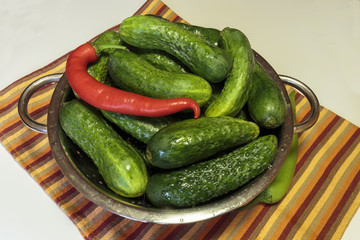 Fresh cucumbers with drops of water in a colander, gherkin as a vegan food.