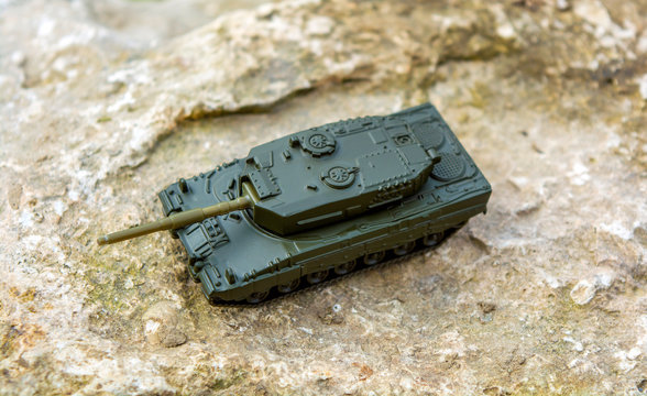 Toy tank on nature background with big stone