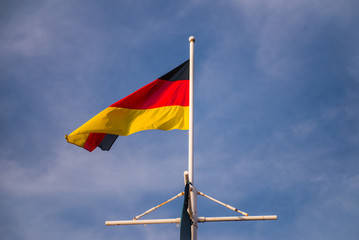 German flag waving in the wind on the stern of a ship sailing on river.
