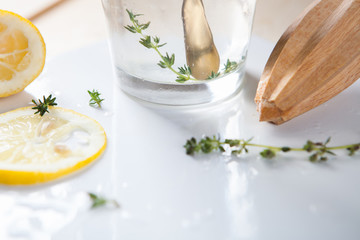 Bleak passing through a glass with lemonade, a juicer and a twig of thyme on a white tray