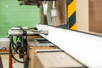 Worker turning on automatic line machinery for cutting in pieces PVC windows and doors sections. Detail close-up shallow depth of field