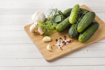 Marinated cucumbers, garlic and spices for salting on the wood surface.