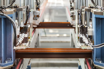 Manual worker assembling glass panels for PVC windows. Factory for aluminum and PVC windows and doors production. Automatic line machine for sticking together PVC sections of window for the final step
