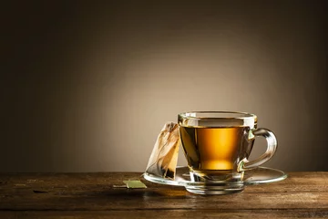 Papier Peint photo Lavable Theé tasse de thé en verre avec sachet de thé sur table en bois