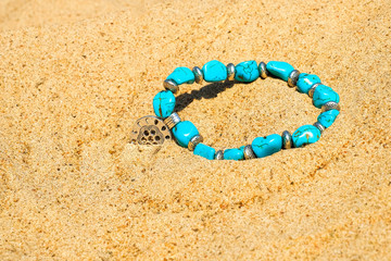 Beautiful semi-precious stone beads on the sea sand.