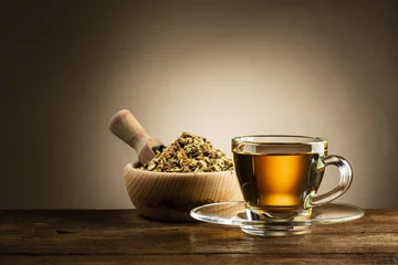 Poster Theé glass cup of tea with herbal tea on wooden table