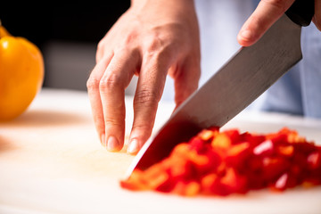 Woman chopping red pepper in kitchen.