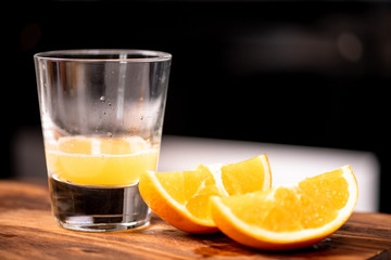 Fresh orange juice in glass with pieces of oranges. On top of wooden board. Heathy lifestyle concept.