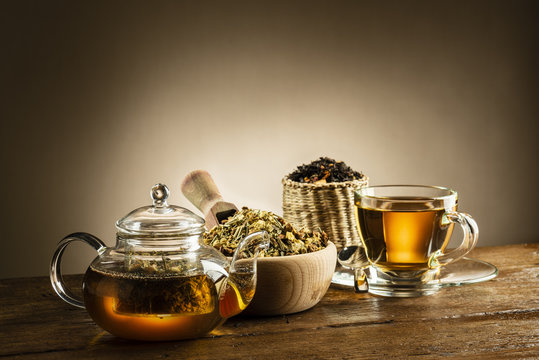 glass teapot with cup and herbal tea on wooden table