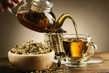 Store enrouleur tamisant Theé théière en verre versant du thé dans une tasse en verre sur une table en bois