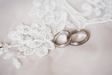  Two wedding rings on a white lace background