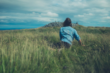 Naklejka na ściany i meble Young woman lying in a field on hilltop