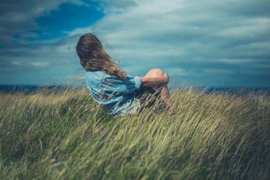Young woman sitting in field on windy day