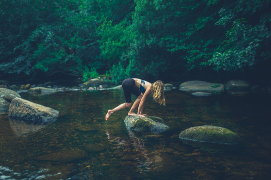 Young woman climbing a rock in the river