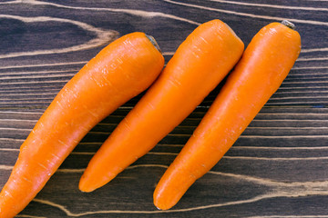 Close up of fresh carrot on rustic wooden background, top view