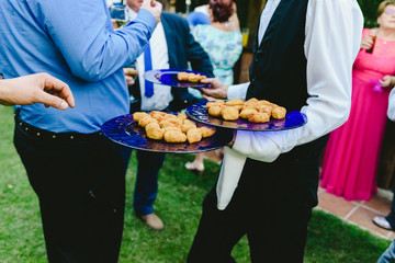 Waiters offering snacks to people who catch them with their hands at a social event