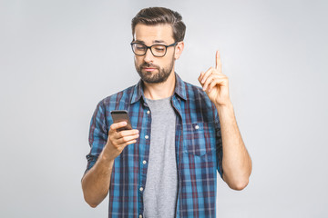 Idea! Young stylish hipster guy dressed in shirt, holds smart phone, reads something attentively,...