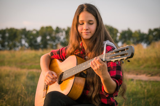 Young girl playing the guitar on meadow