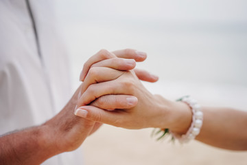 The hands of a man and a woman hold each other tightly. Concept of wedding and relationship.